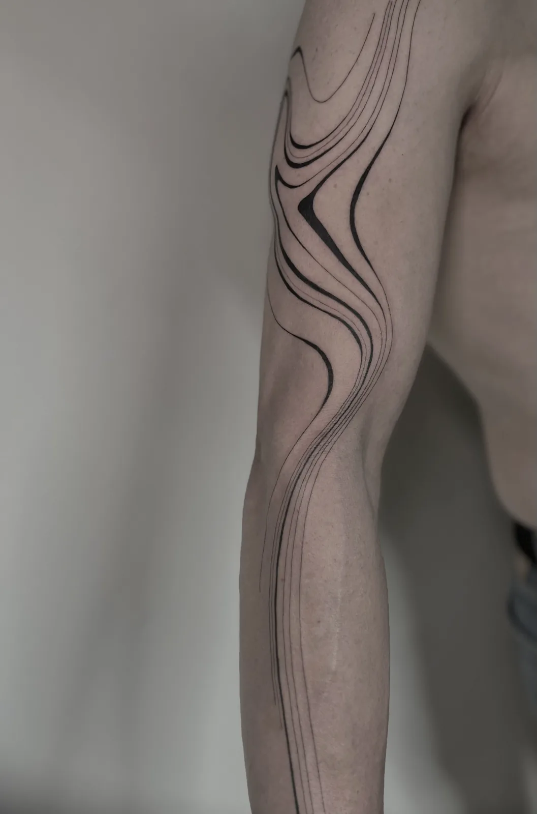 Liquid minimalist fine-line waves flowing down the arm, GAR Tattoo